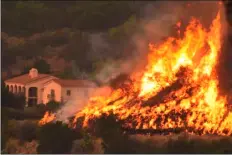  ??  ?? In this Thursday photo provided by the Santa Barbara County Fire Department, flames from a back firing operation underway rise behind a home off Ladera Lane near Bella Vista Drive in Santa Barbara. AP PHOTO