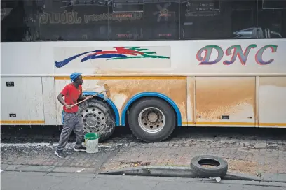  ??  ?? CLEANING UP. A man washes a bus on a street corner in Braamfonte­in.