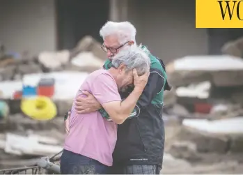  ?? BORIS ROESSLER / DPA VIA AP ?? Two brothers weep in each other's arms on Monday in front of their parents' house, which was destroyed by the flood in Altenahr, Germany. At least 165 people died and dozens are still missing in the floods that hit the western region.