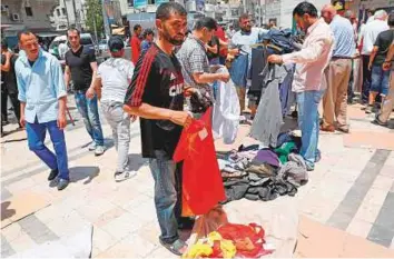  ?? AFP ?? Jordanians buy second-hand clothes in an open air market in central Amman on Friday. Jordan’s authoritie­s have shelved a proposed income tax hike after a week of protests.