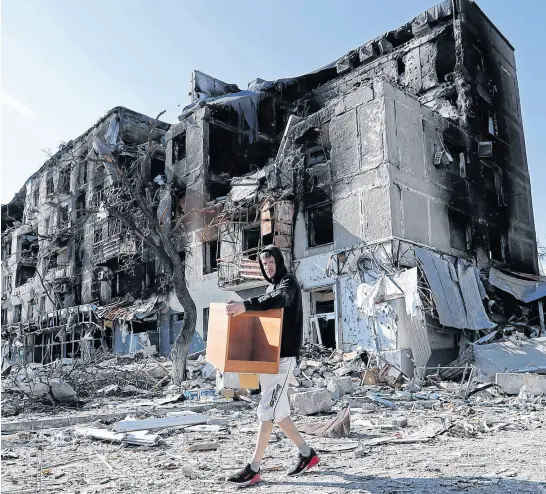  ?? REUTERS ?? A local resident takes furniture out of an apartment building heavily damaged during Ukraine-russia conflict in the southern port city of Mariupol, Ukraine, Thursday.