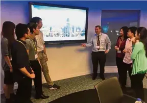  ??  ?? Johnson (fourth from right) speaking to the Chevening scholars at the BAE Systems Applied Intelligen­ce Nerve Centre in London.