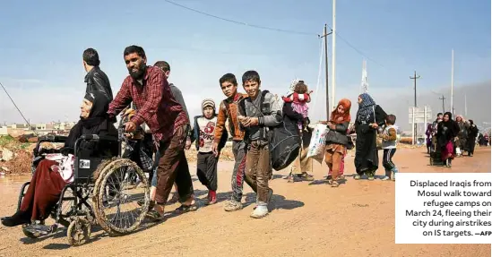  ?? —AFP ?? Displaced Iraqis from Mosul walk toward refugee camps on March 24, fleeing their city during airstrikes on IS targets.