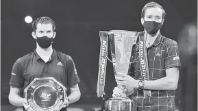  ?? — Gambar AFP ?? UNTUK KENANGAN: Medvedev (kanan) dan Thiem memakai pelitup muka bergambar dengan trofi selepas perlawanan di O2 Arena di London kelmarin.
