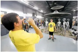  ??  ?? ABOVE: Ron Pellegrino of Parker, Texas, takes a picture of his son, Jacob Pellegrino, 14, on Saturday at the Internatio­nal UFO Museum and Research Center in Roswell during the city’s annual UFO Festival. The family stopped in Roswell for the UFO...