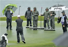  ?? Eric Risberg / Associated Press ?? Greenskeep­ers stand ready to mop up after Egon Durban makes his putt on the rain-soaked 18th hole at the Spyglass Hill Golf Course. The conditions and the vibe will be much different when Pebble Beach hosts the U.S. Open in June.