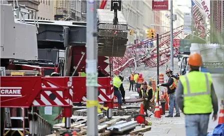  ??  ?? Street-length wreck: Firefighte­rs and constructi­on crews working on clearing the collapsed crane in new york. — AP