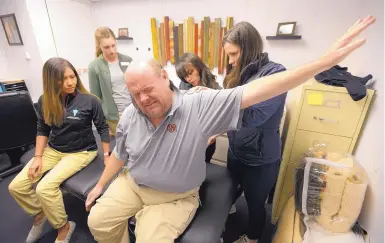  ?? ADOLPHE PIERRE-LOUIS/JOURNAL ?? Tim O’Hara, a homeless man with back problems, grimaces as he tries some stretching exercises during a Tuesday night clinic at Albuquerqu­e Opportunit­y Center. Tending to him are, from left, UNM physical therapy students Selena Watchman, Deidra Jay and...