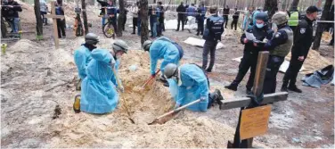  ?? Agence France-presse ?? ±
Forensic technician­s dig a grave in a forest on the outskirts of Izium in eastern Ukraine on Friday.