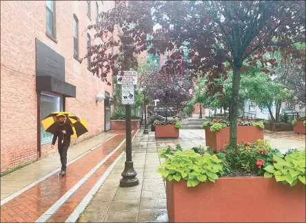  ?? Veronica Del Valle / Hearst Connecticu­t Media ?? A man walks as the rain from Tropical Storm Henri hits Stamford on Sunday. Henri was downgraded from a hurricane to a tropical storm as the storm took a turn eastward before hitting land.