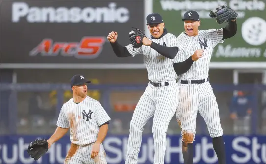  ?? AP-Yonhap ?? New York Yankees center fielder Brett Gardner, left, watches as Yankees left fielder Giancarlo Stanton, center, and Yankees fielder Aaron Judge leap in the air after the Yankees 11-4 victory over the Tampa Bay Rays in a baseball game in New York,...