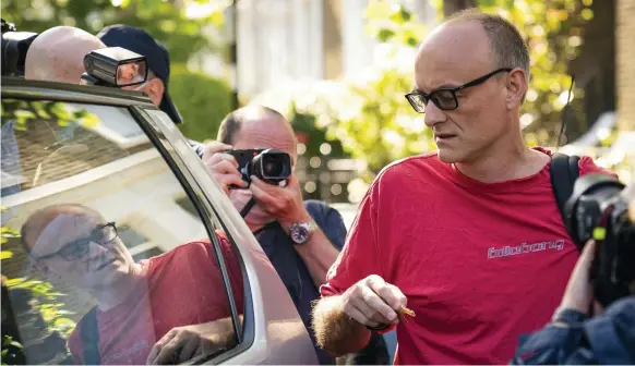  ?? AP; AFP ?? UK Prime Minister Boris Johnson’s senior aide, Dominic Cummings, leaves his London home yesterday; left, a message given by Mr Johnson that urged the British people to remain at home is played on a big screen on the back of a vehicle parked outside Mr Cummings’ house