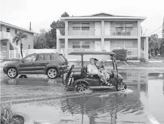  ?? VIA THE ASSOCIATED PRESS] ?? People drive through flooded areas Thursday after Tropical Storm Eta battered Tampa Bay, leaving damage from flooding and wind in communitie­s throughout, in Gulfport, Fla. [MARTHA ASENCIO RHINE/ TAMPA BAY TIMES