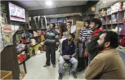  ?? — AP ?? JAMMU: People watch Indian Prime Minister Narendra Modi addressing the nation, on television at a grocery store in Jammu yesterday.