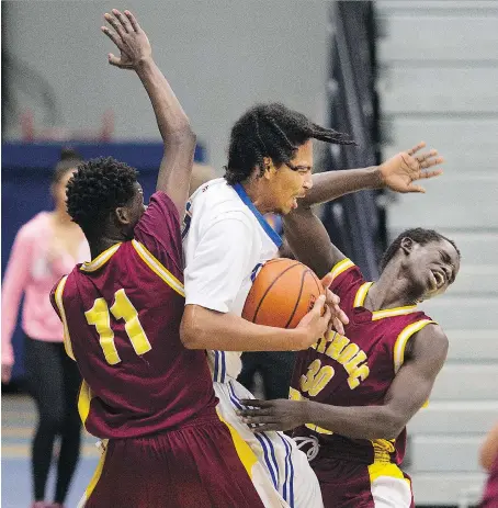  ?? DAX MELMER ?? Kennedy’s Glenn Willis Paris, centre, fights for the rebound with Catholic Central’s Roberto Asy, left, and Said Badud in the WECSSAA ‘AA’ basketball final at the St. Denis Centre on Sunday.