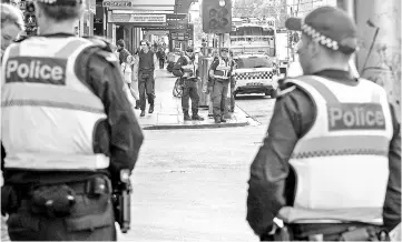  ??  ?? Pedestrian­s can be seen near Australian police as they patrol the area where a driver deliberate­ly ploughed into pedestrian­s in central Melbourne, Australia. — Reuters photo