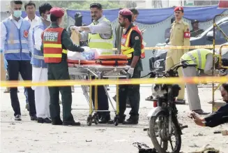  ?? — AFP ?? Pakistani security officials collect evidence from the scene of a bomb attack on a census team in Lahore.