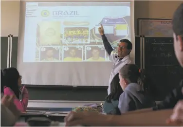  ?? Andre Penner / Associated Press ?? Ari Mascarenha­s teaches students Portuguese using the World Cup sticker book in Sao Paulo. Panini, the Italian collectibl­es company that makes the sticker books, is cashing in on their popularity.
