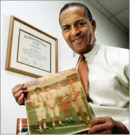 ??  ?? In this 2005 photo Dallas attorney and former Texas football player Julius Whittier holds a newspaper clipping from 1971 featuring Whittier with teammates Bruce Cannon, Greg Dahlberg, and coach Darrell Royal in Dallas.
