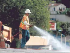  ??  ?? A WORKER sprays down streets in an attempt to control dust from a pipeline that is part of a project to retire the Silver Lake and Ivanhoe reservoirs.