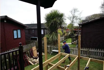  ?? (Dylan Martinez/Reuters) ?? A WORKER extends decking to a mobile home at The Thatches Holiday Village in Modbury, England, earlier this month. The 90-lodge Thatches park in the county of Devon has seen a rise in bookings and inquiries since the vote to leave the European Union...