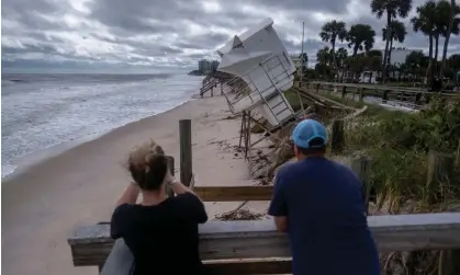  ?? Ricardo Arduengo/Reuters ?? A couple looks at a damaged lifeguard tower following the passage of Hurricane Nicole in Vero Beach, Florida, on Thursday. Photograph: