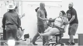  ??  ?? An injured woman is wheel away outside the Tropicana during the shooting at the Route 91 Harvest Festival on the Las Vegas Strip on Oct. 1.