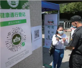  ??  ?? A graduate shows her health code at the entrance of Wuhan University on June 8