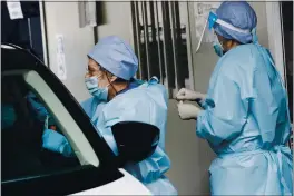  ?? LUCA BRUNO — THE ASSOCIATED PRESS ?? A medical staffer takes swabs as she tests for COVID-19 at a drive-through at the San Paolo hospital in Milan, Italy, Wednesday.