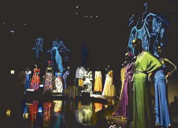  ??  ?? A stolen shot, but the descriptio­n comes from a postcard bought from the museum store: (from left) “Yves Saint Laurent and art,” “an invitation to the ball,” “extraordin­ary gardens.” Above, an audiovisua­l projection presents the details of the clothes....