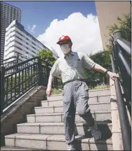  ??  ?? Tamura walks down stairs in Tokyo.