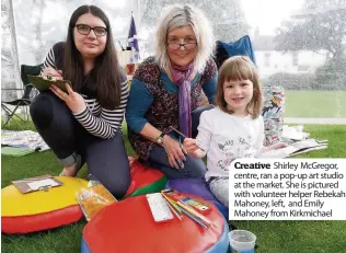  ??  ?? Creative Shirley McGregor, centre, ran a pop-up art studio at the market. She is pictured with volunteer helper Rebekah Mahoney, left, and Emily Mahoney from Kirkmichae­l