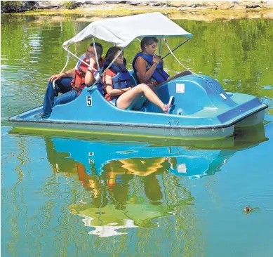  ?? GREG SORBER/JOURNAL ?? From left, Jerome Michelbach, Vanessa Chavez and Aaliyah Saavadra, all of Albuquerqu­e, take a leisurely pedal boat ride at Tingley Beach on Monday. Michelbach said that even though they were on the water, it was still a “little hot.” Meteorolog­ists say...