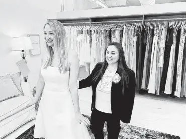  ?? Gilded Social via AP ?? In this photo provided by Gilded Social, a bridal shop in Columbus, Ohio, owner Tanya Rutner Hartman helps customer Cristin Lee try on a gown. Vaccinatio­ns have helped ease COVID-19 limits as the events industry looks for a slow but steady recovery.