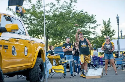  ?? Haldan Kirsch/ Post- Gazette ?? Steelers fan Craig Gehm, center, of Cranberry, plays cornhole next to his customized Steelers Dodge Ram truck Friday outside Heinz Field before the team’s preseason opener against the Tampa Bay Buccaneers. Mr. Gehm said he bought the truck from former Steelers kicker Jeff Reed, who works at a car dealership in Charlotte, N. C.