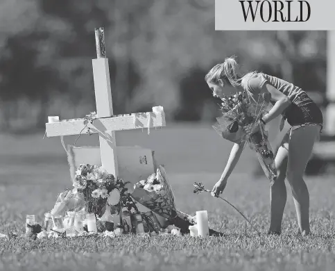  ?? GERALD HERBERT / THE ASSOCIATED PRESS ?? A woman places flowers Friday at one of 17 crosses placed for the victims of the shooting at Marjory Stoneman Douglas High School in Florida.