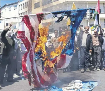  ?? PICTURE: ATTA KENARE/AFP VIA GETTY ?? Demonstrat­ors burn US and Israeli flags at the funeral of Iranians killed in Damascus