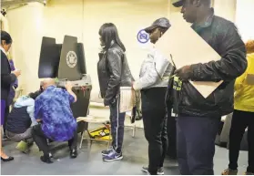  ?? Bebeto Matthews / Associated Press ?? Polling site officials (left) check on a voting scanner after it jammed, forcing voters in the Parkcheste­r community of New York to manually file their ballots until a repair was made.