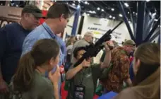  ?? ADREES LATIF/REUTERS ?? Family members watch 11-year-old Mark take aim with an assault rifle on the exhibit floor of the National Rifle Associatio­n’s annual meeting.