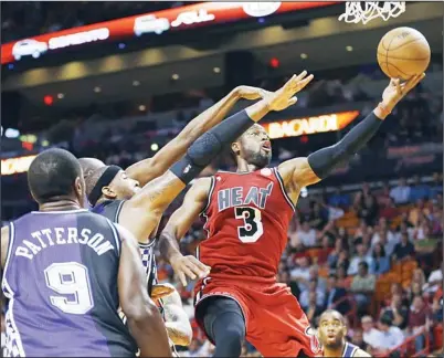  ??  ?? Sacramento Kings’ Patrick Patterson (9) watches as DeMarcus Cousins (15) tries to block Miami Heat’s Dwyane Wade (3) during the
first half of an NBA basketball game in Miami, Feb 26. (AP)