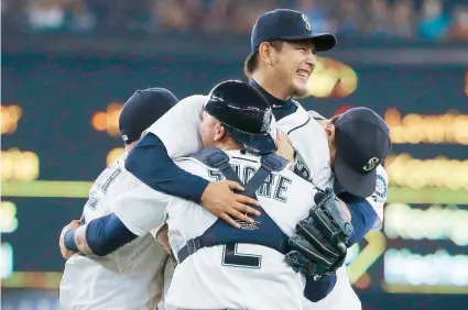  ??  ?? Hisashi Iwakuma, de los Marineros, es abrazado por sus compañeros de equipo luego de completar ayer un juego sin hits ni carreras ante los Orioles de Baltimore.
