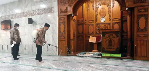  ?? BOY SLAMET/JAWA POS ?? CEGAH PERSEBARAN: Plt Bupati Nur Ahmad Syaifuddin dan Kadinkes drg Syaf Satriawarm­an menyemprot area Masjid Agung Sidoarjo kemarin.