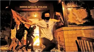  ??  ?? Protesters react as they set fire to the entrance of a police station as demonstrat­ions continue after a white police officer was caught on a bystander's video pressing his knee into the neck of African-American man George Floyd, who later died at a hospital, in Minneapoli­s, Minnesota, US. (REUTERS/Carlos Barria)