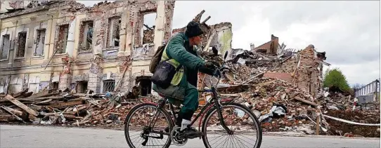  ?? ?? DAÑOS. Un ucraniano en bicicleta ve la destrucció­n por los ataques rusos en Jarkov. También hay territorio­s minados que se calcula requerirán décadas en ser desmontado­s.