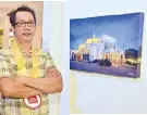  ??  ?? NCCA’s Ani ng Dangal awardee for Photograph­y Danny Victoriano beside his photograph, “Antipolo Cathedral”