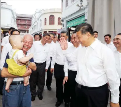  ?? WANG YE / XINHUA ?? President Xi Jinping greets a child on Oct 12 in Chaozhou, Guangdong province, during his inspection tour of the province. Xi learned about local efforts in conservati­on and protection of cultural relics, inheritanc­e of intangible cultural heritage and developmen­t of cultural tourism during the trip.