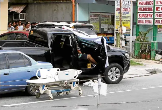  ?? —RICHARD A. REYES ?? BRAZEN ATTACK A piece of cloth shrouds the front passenger section of the pickup truck and the bullet-riddled body of Trece Martires City Vice Mayor Alexander Lubigan.