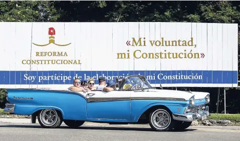  ?? AP ?? In this October 2, 2018 photo, tourists take a joy ride in a vintage convertibl­e car, past a billboard promoting constituti­onal reform with the Spanish messages: “My will, my Constituti­on” at right, and “I’m a participan­t in the making of my Constituti­on” in Havana, Cuba.