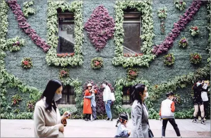  ?? TONG YU / CHINA NEWS SERVICE ?? Tourists enjoy the moment by a beautifull­y decorated wall at the Italian Style Town in Tianjin in May.