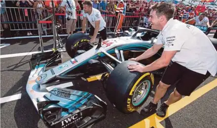  ?? AFP PIC ?? Pit crew members push Lewis Hamilton’s Mercedes at the Circuit Paul Ricard in Le Castellet on Thursday.